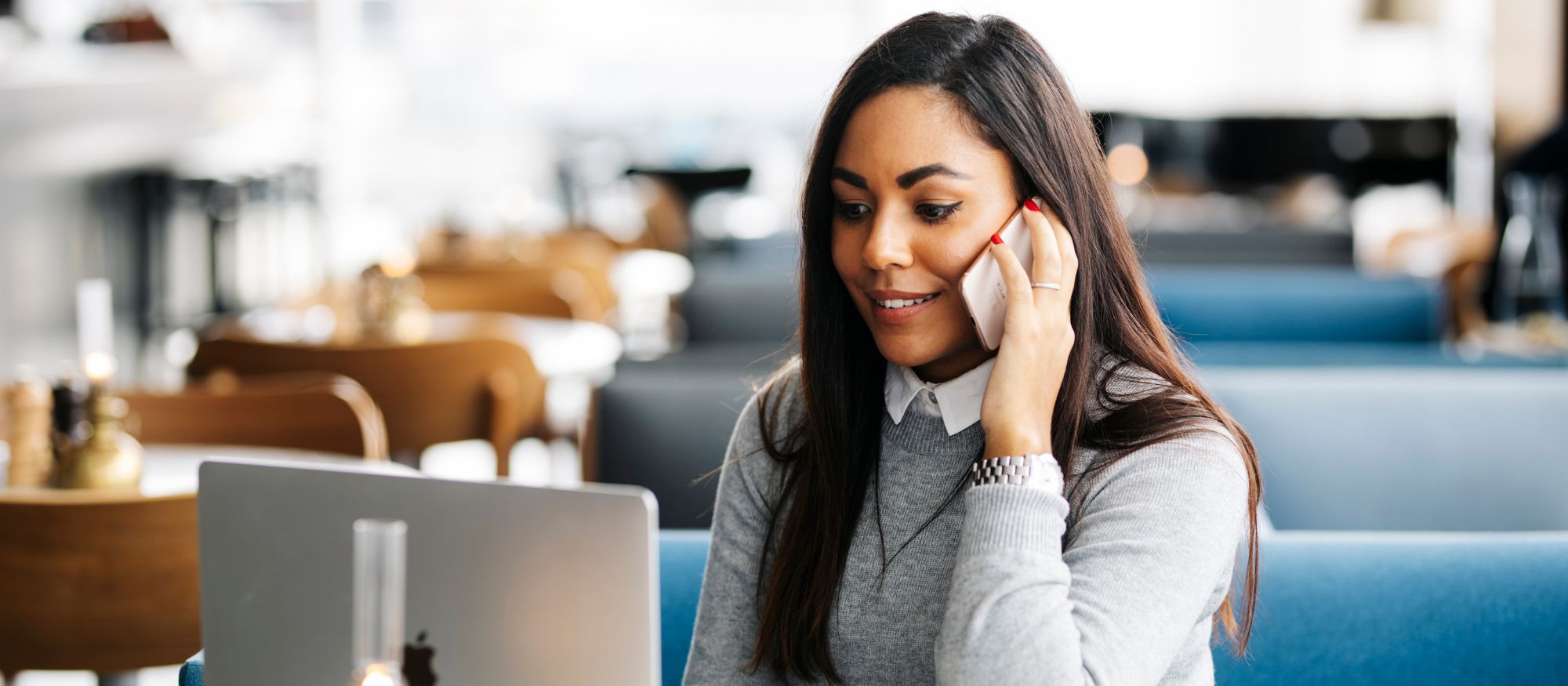 Kvinnlig entreprenör vid datorn som pratar i telefon